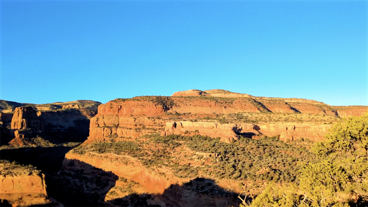 Beautiful morning light hits canyon country. Orange and red rocks, blue sky, green scrub brush